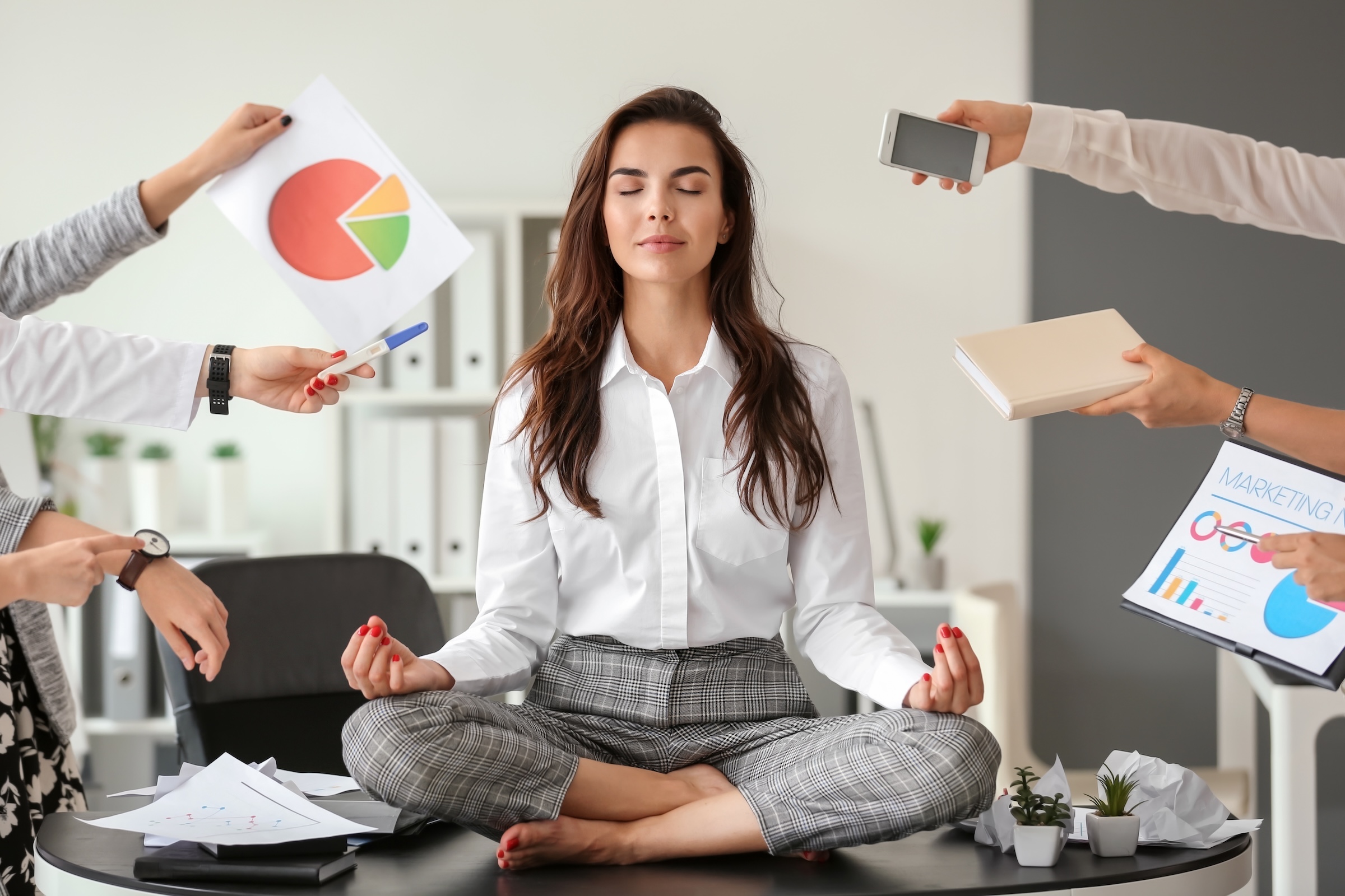 Businesswoman meditating in office to manage stress and promote heart health amidst a busy schedule.